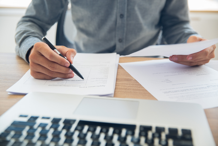 person reviewing documents in front of laptop